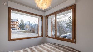A bedroom with a bed, two windows, and a ceiling light fixture. - Apartment "Le Pacardou" with Mountain View, Private Terrace and Wi-Fi (Saint-Gervais-Les-Bains)