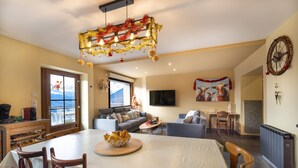 A dining area with a table, chairs, a bowl of bread, a television, and a sofa. - Apartment "Le Pacardou" with Mountain View, Private Terrace and Wi-Fi (Saint-Gervais-Les-Bains)