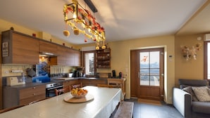 A modern kitchen with wooden cabinets, a central island with a bowl of fruit, and a dining area with a bench. - Apartment "Le Pacardou" with Mountain View, Private Terrace and Wi-Fi (Saint-Gervais-Les-Bains)