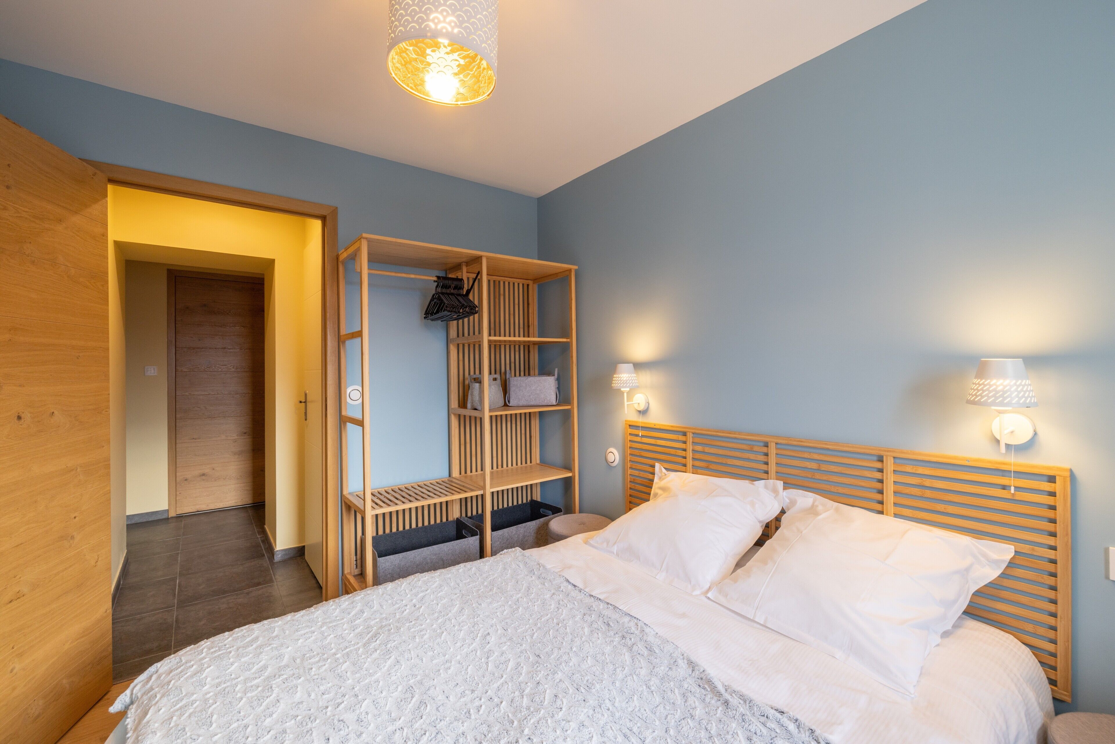 Ein Schlafzimmer mit einem Bett, einem Holzkopfteil, einem Kleiderschrank und einem Regal.