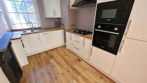 A kitchen with white cabinets, a wooden countertop, a Bosch oven, and a window providing natural light. -  Hull Spacious Apartment 7 (Hull)