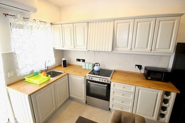 A compact kitchen with white cabinets, a stove, oven, and a microwave.