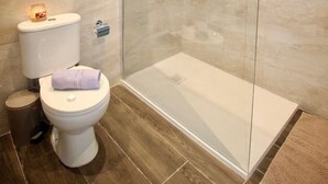 A modern bathroom with a glass-enclosed shower, a toilet, and a bidet.