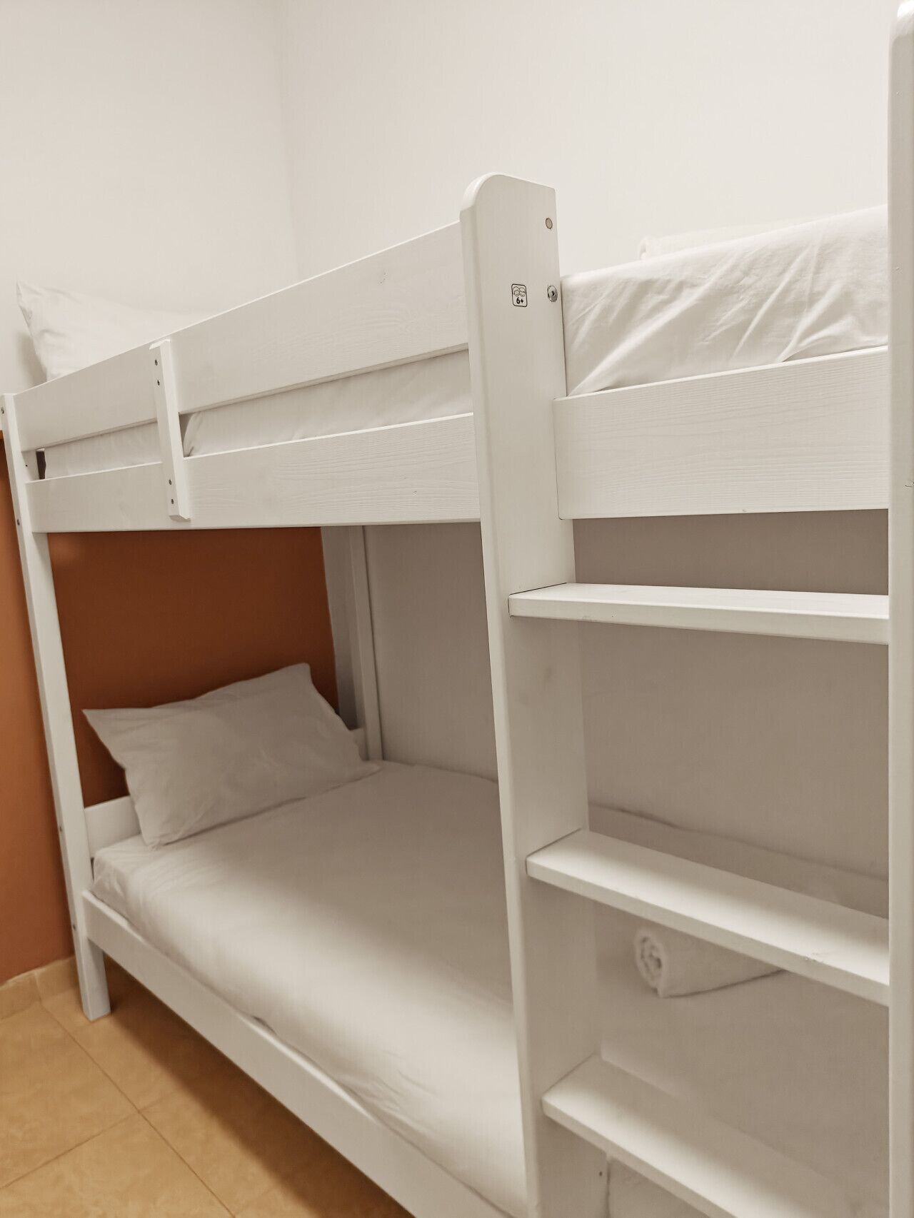 A bunk bed with a headboard, a shelf, and a mattress.