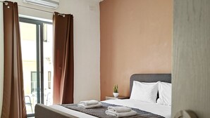 Et hotelværelse med en seng, et natbord, en potteplante og en aircondition.