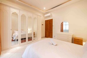 A bedroom with a large bed, a wardrobe with mirrored doors, a wooden door, a dresser, and a mirror. - 2 bedroom by Sliema promenade (Tas-Sliema)