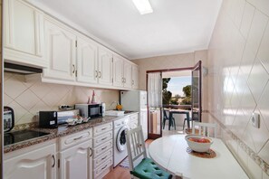 A compact kitchen with white cabinets, a microwave, toaster, and a sink. - Apartment 'Tenis Golfmar' with Shared Pool, Wi-Fi and Air Conditioning (Vialmoura)