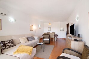 Una sala de estar con sofá, sillas, una mesa de comedor y televisor.