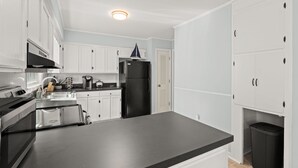 A modern kitchen with white cabinets, a black refrigerator, a stainless steel oven, and a black countertop.