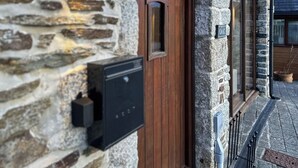 A stone building with a wooden door, a mailbox, and a window. - 1 bedroom accommodation in Falmouth (Falmouth)