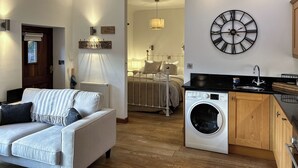 A compact living space with a sofa, a washing machine, a bed, and a wall clock. - 1 bedroom accommodation in Falmouth (Falmouth)