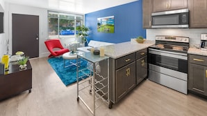 A modern kitchen with dark cabinets, stainless steel appliances, and a blue accent wall. - Beachside Getaway on Emerald Coast (Fort Walton Beach)