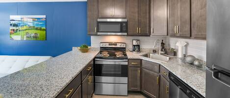 Una cocina moderna con armarios de madera oscura, electrodomésticos de acero inoxidable y encimera de granito.