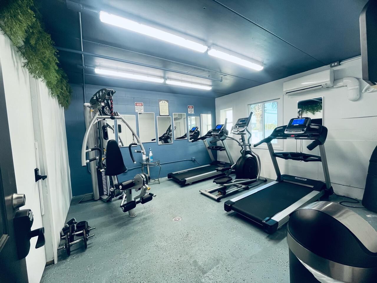 Un gimnasio con cintas de correr, máquinas de pesas y una bicicleta estática de pared.