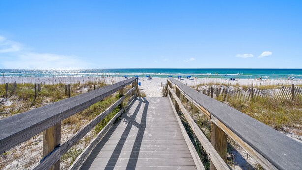 A wooden boardwalk leading to a beach with clear skies. - Beachside Getaway on Emerald Coast (Fort Walton Beach)