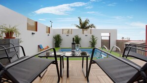 Un espace aménagé au bord de la piscine, avec des chaises longues, une table et la piscine elle-même.