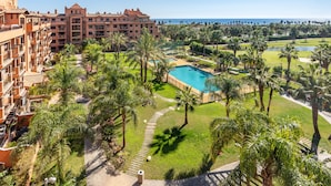Een resort met een zwembad, palmbomen en uitzicht op de oceaan.