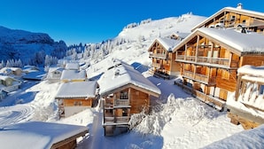 A snow-covered mountain resort with wooden buildings, a ski lift, and a clear blue sky. - Apartment "Superb Duplex - Résidence Alpine" with Private Terrace, Balcony and Wi-Fi (Arâches-la-Frasse)