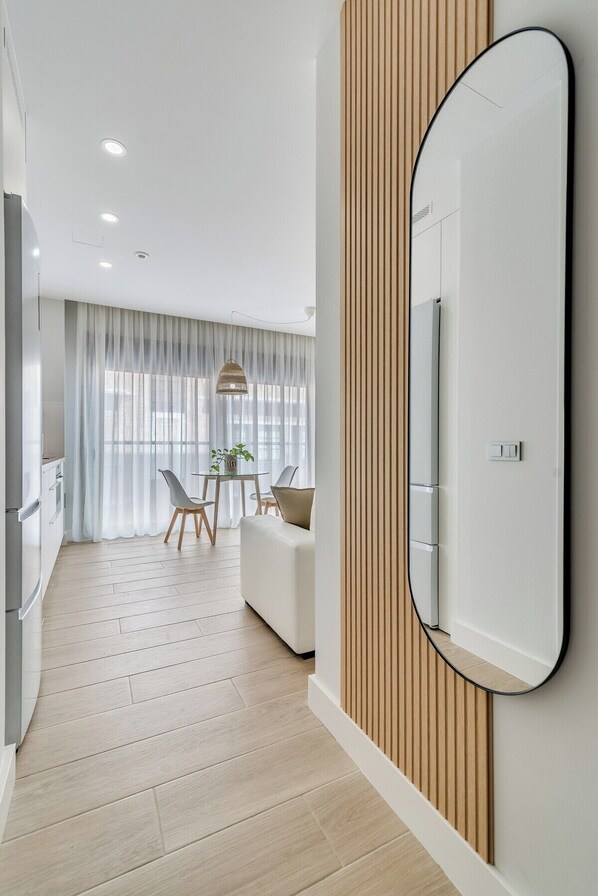 Une chambre d’hôtel moderne dotée d’un grand miroir, de lambris en bois, d’un coin repas avec une table et des chaises, et d’un espace cuisine.