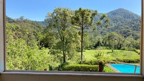 A view from a window overlooking a lush green landscape with a mountain in the background. - Casa do Rio, Rio Bonito de Lumiar (Lumiar)