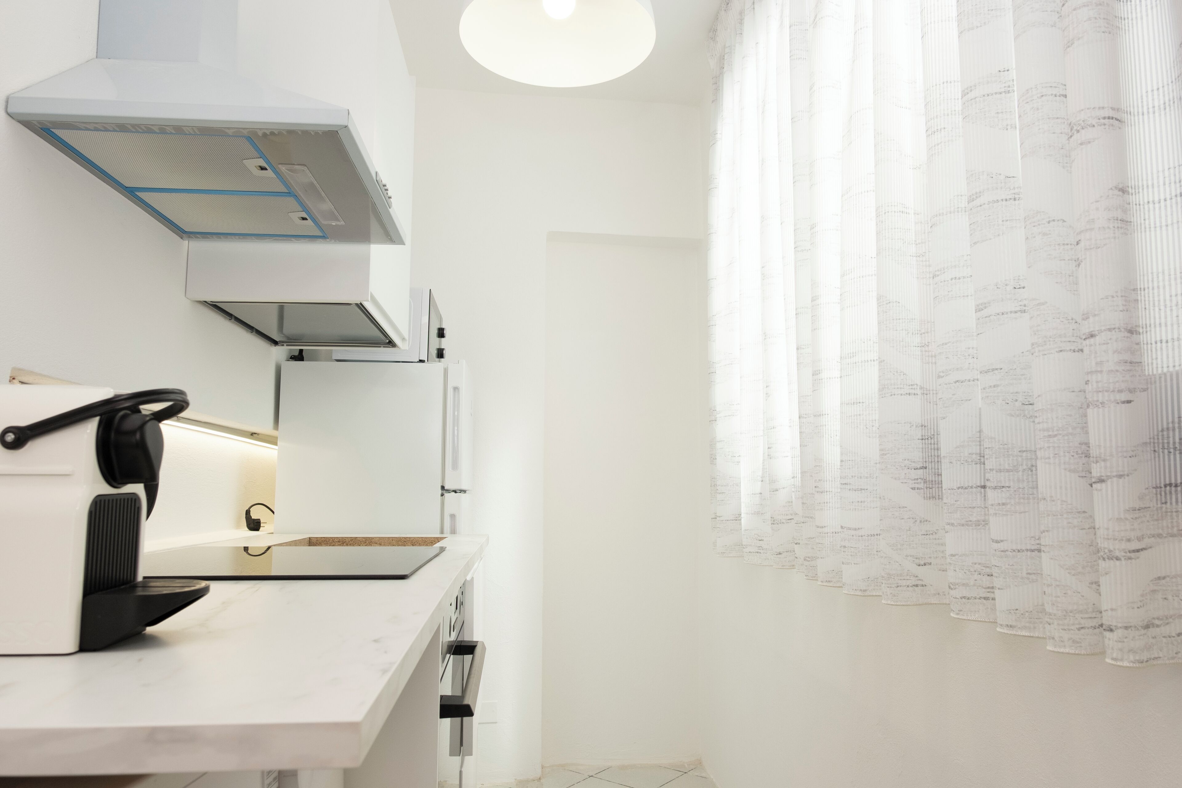 A modern kitchen with a built-in stove, a coffee machine, and a range hood.