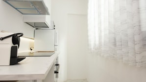 Una cocina moderna con estufa integrada, cafetera y campana extractora.