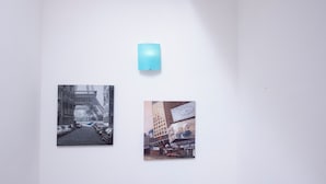Una pared con dos fotografías enmarcadas y una lámpara azul.
