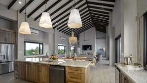 Een ruime keuken met een groot kookeiland, houten kasten en moderne apparaten.