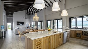 Een ruime keuken met een groot eiland, houten keukenkastjes en uitzicht op het water.