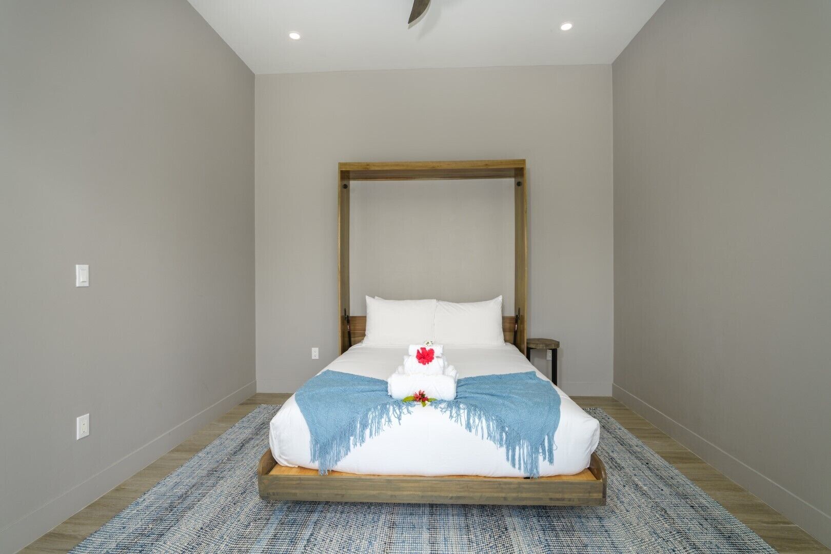 A bedroom with a large bed, a wooden headboard, a nightstand, and a blue throw blanket.