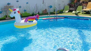 Een buitenzwembad, parasols bij het zwembad en ligstoelen