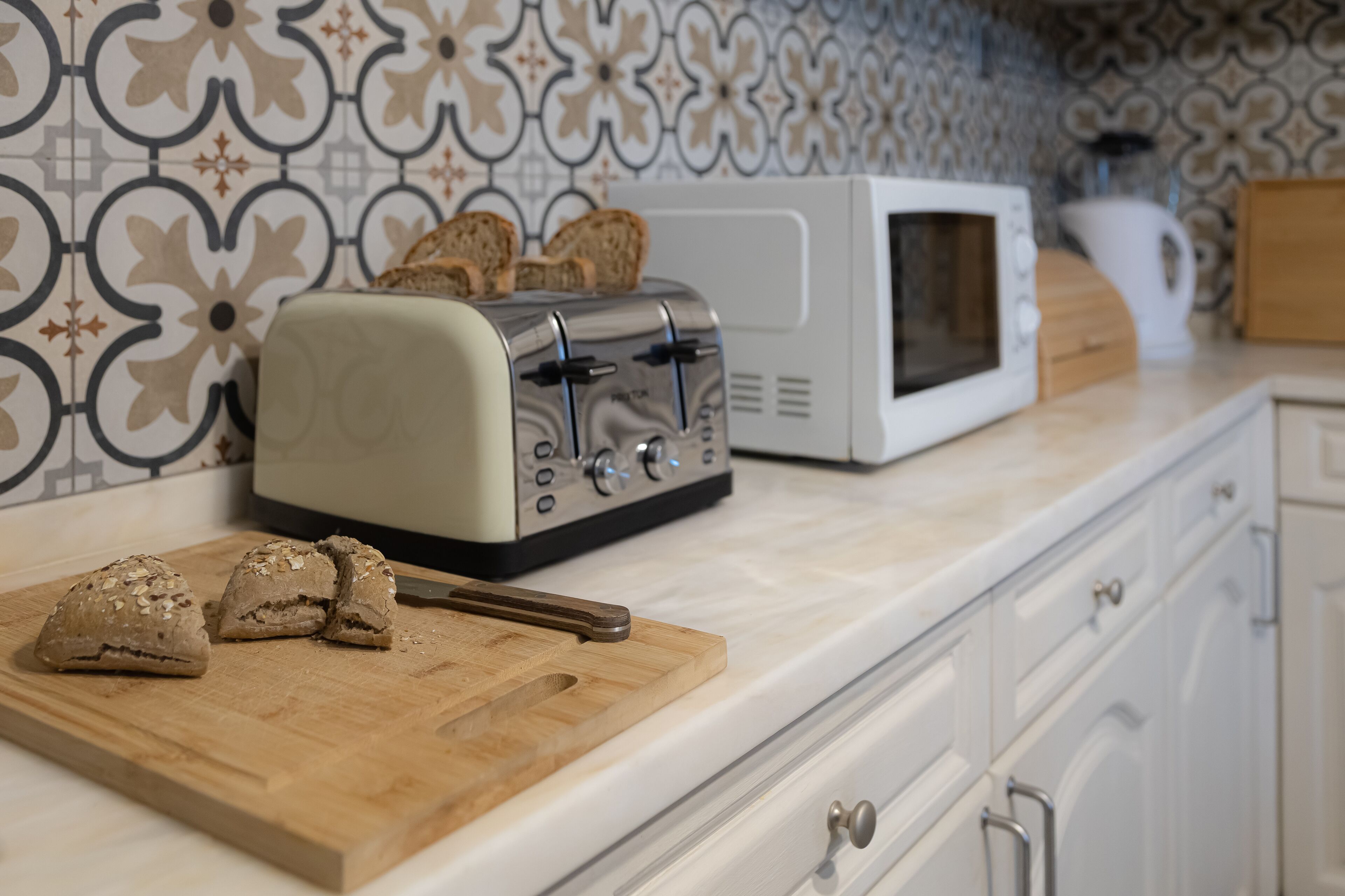 Eine Küche mit einem Toaster, einer Mikrowelle und einem Schneidebrett mit Brotscheiben.