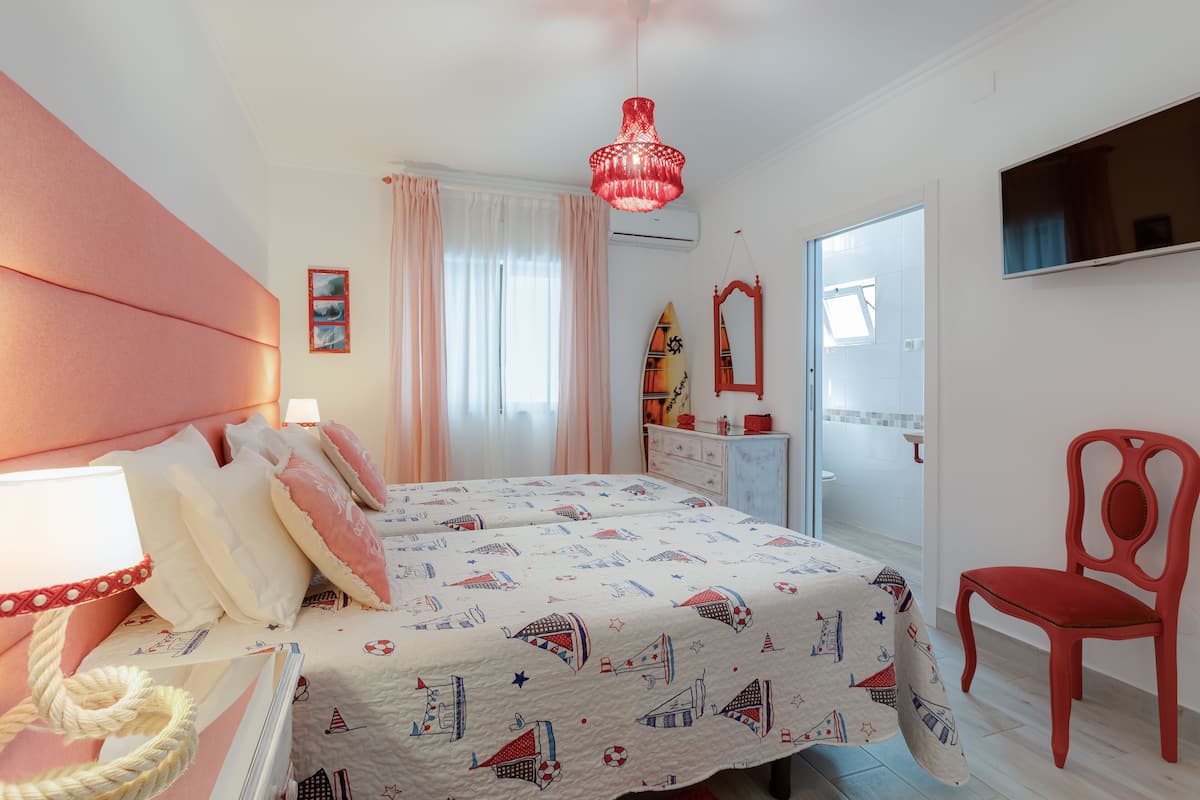 A bedroom with a bed, a chair, a dresser, a mirror, and a hanging light fixture.