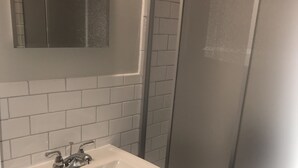 Un bany amb un rentapans, un mirall i una cabina de dutxa.