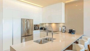 A modern kitchen with stainless steel appliances, a double sink, and a long countertop. - 3 Bedroom/4 Bathroom Luxury Condominium  (Cabo San Lucas)