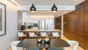 A modern kitchen with a central island, white chairs, and pendant lighting. - 3 Bedroom/4 Bathroom Luxury Condominium  (Cabo San Lucas)