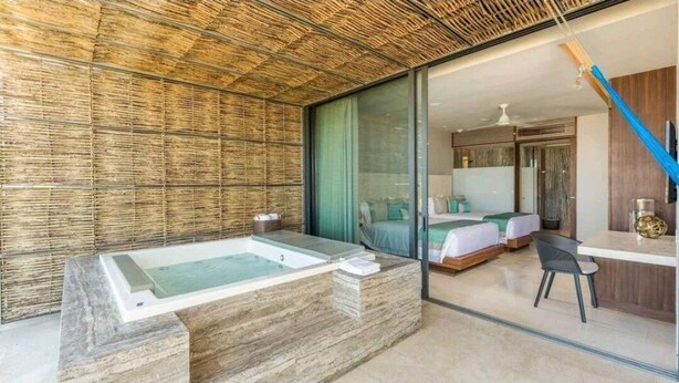 A modern bathroom with a large bathtub, a shower area, and a glass-enclosed bedroom with a bed and a desk. - 3 Bedroom/4 Bathroom Luxury Condominium  (Cabo San Lucas)