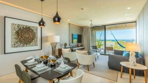 A modern hotel room with a dining area, a living area with a view, and a large window overlooking the ocean. - 3 Bedroom/4 Bathroom Luxury Condominium  (Cabo San Lucas)