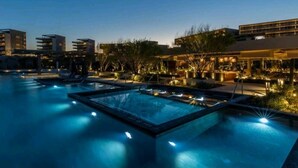 A nighttime swimming pool area with multiple pools, lounge chairs, and illuminated plants. - 3 Bedroom/4 Bathroom Luxury Condominium  (Cabo San Lucas)