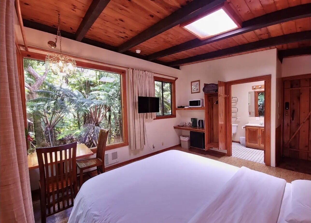 Un dormitorio con una cama grande, un escritorio, una silla, un televisor y vistas al exterior.