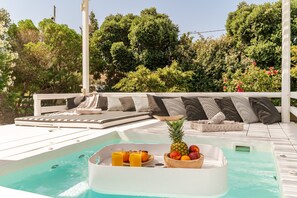 Una piscina sul tetto con sedie a sdraio, una ciotola di frutta e una vasca idromassaggio.