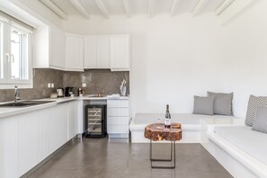Una cucina moderna con mobili bianchi, una cantinella integrata e un angolo salotto con un tavolo rotondo in legno.