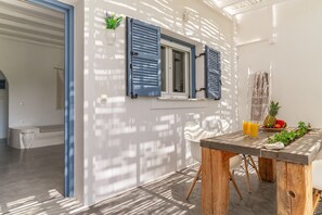 Une cuisine moderne avec une table à manger, une fenêtre avec des volets bleus et une vue sur l’extérieur.