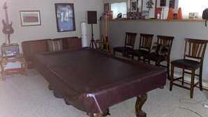 A room with a pool table, a guitar, a Texaco gas pump, and various framed pictures on the walls. - Large house centrally located (Colorado Springs)