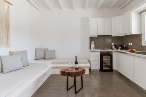 Eine moderne Küche mit weißen Schränken, einem Einbauofen und einem Essbereich mit Holztisch und Bank.