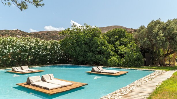 Una piscina con sillas de descanso, una terraza de madera y vistas a colinas.