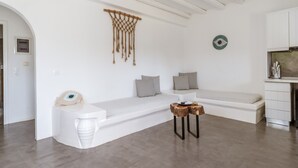 Un espacio de estar moderno y minimalista con un banco blanco, un colgador decorativo de macramé y una pequeña mesa de madera.