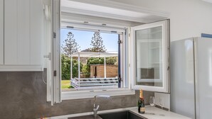 Una cocina con ventana, pileta y una botella de champán.