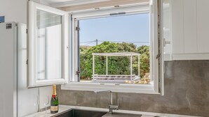 Eine Küche mit Fenster, Spüle, einer Champagnerflasche und einem Teller mit Speisen.