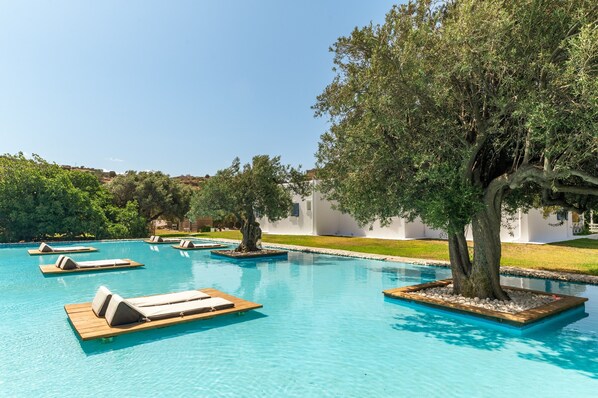 A pool area with lounge chairs and trees, surrounded by a white building.
